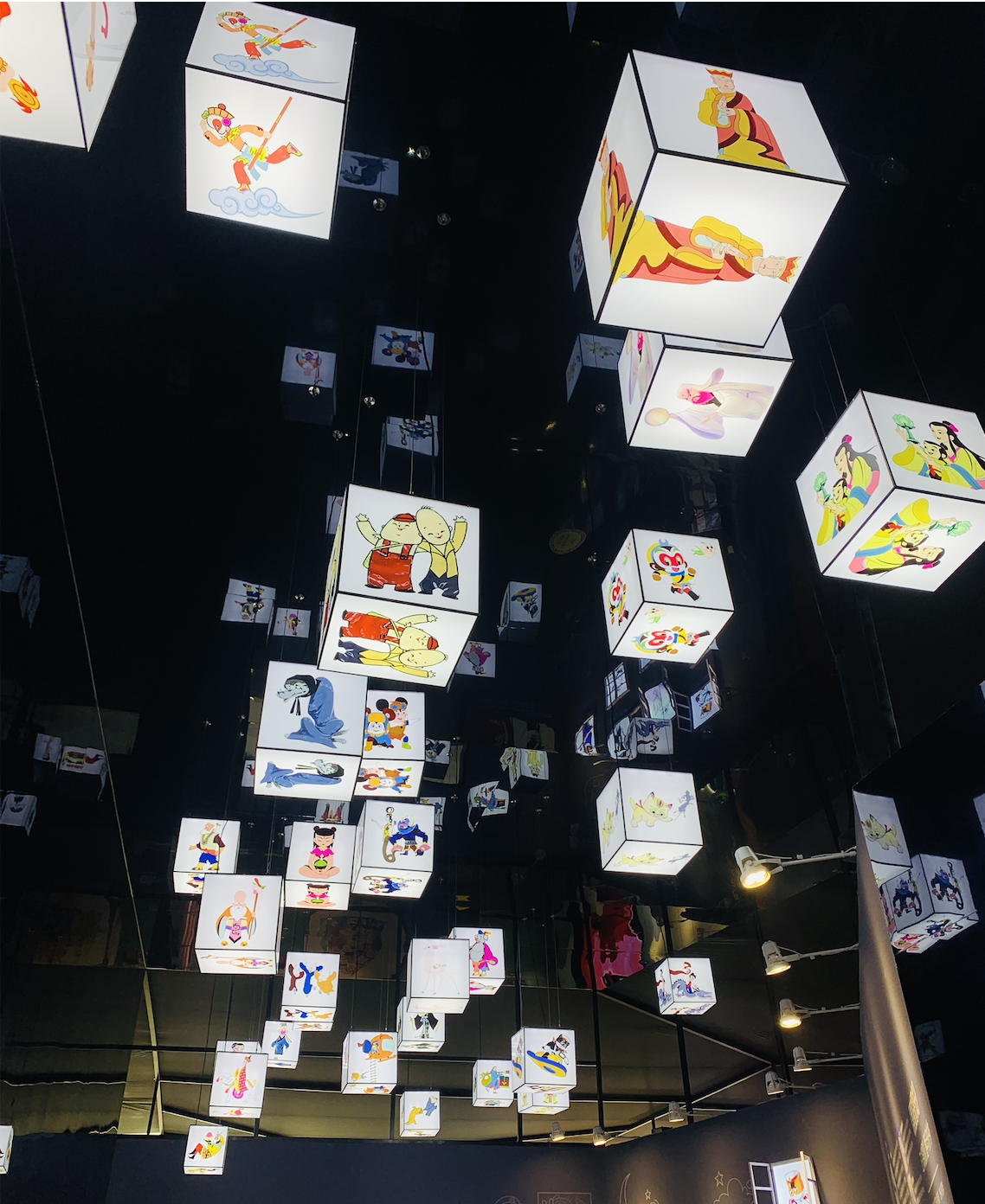 Hanging illuminated displays featuring characters from classic Chinese animated films at an exhibition.